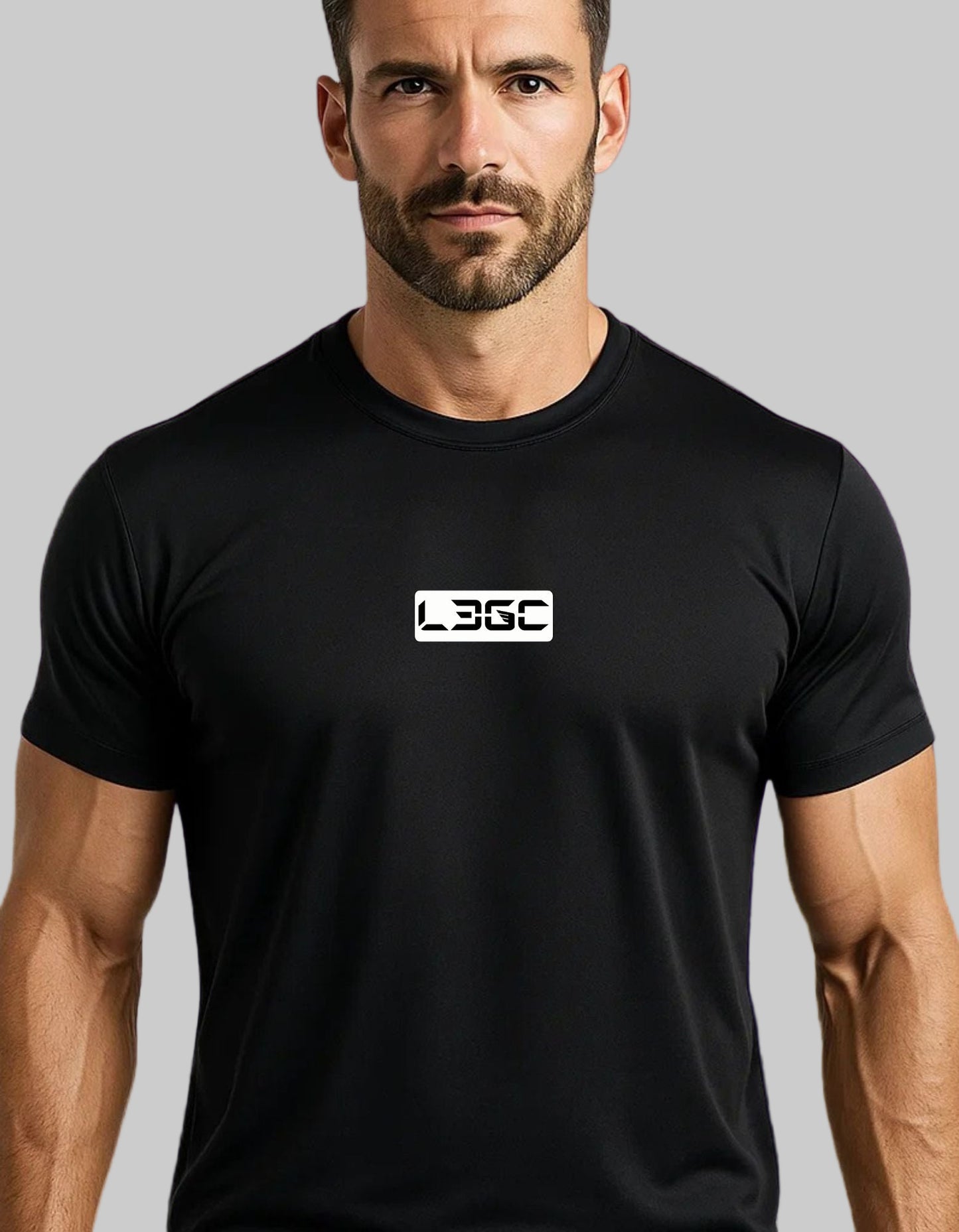 Man wearing a black t-shirt with a logo against a purple brick wall