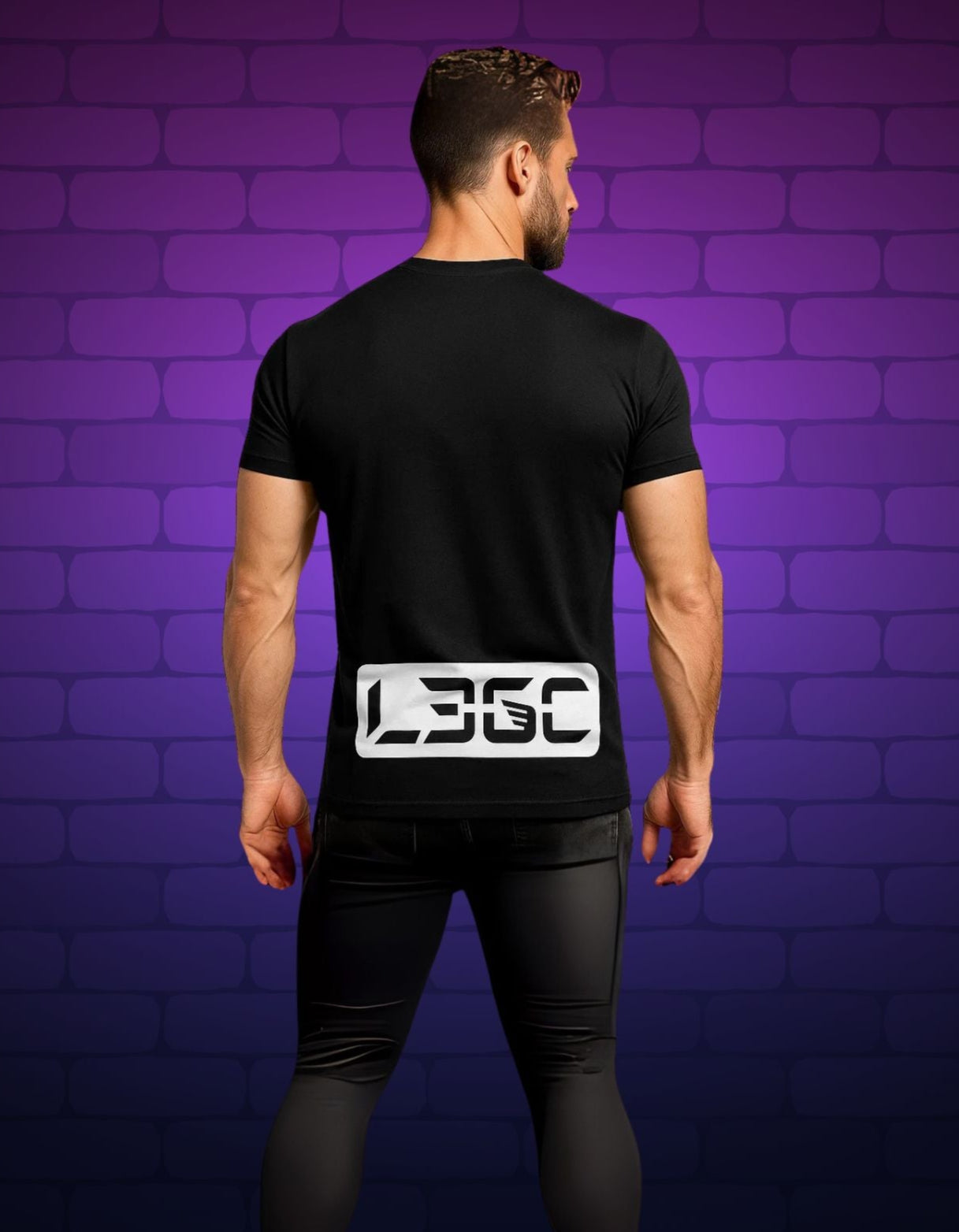 Person wearing a black t-shirt with a logo on the back against a purple brick wall.
