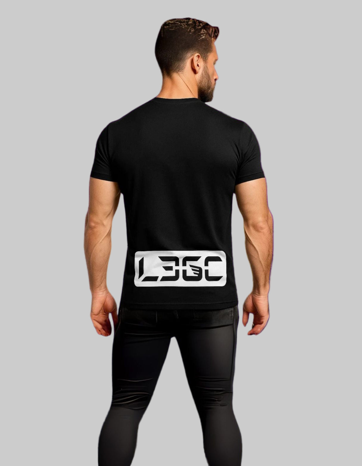 Person wearing a black t-shirt with a logo on the back against a purple brick wall.