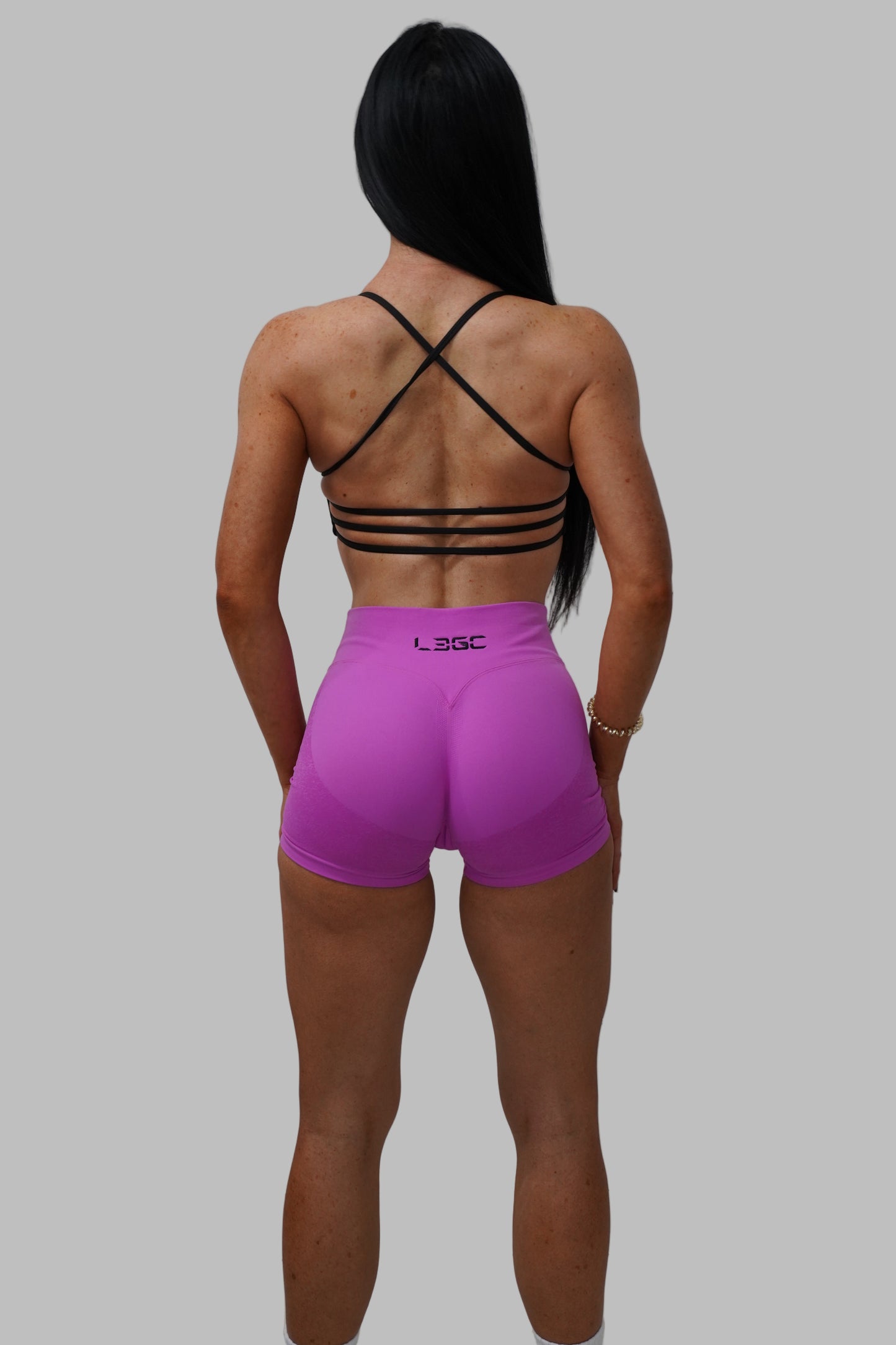 Person wearing a black strappy top and pink shorts.