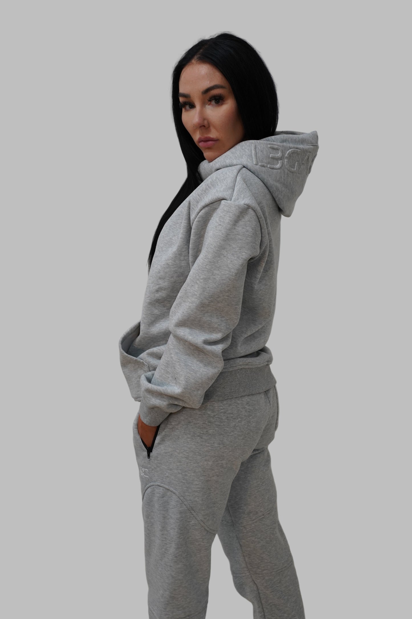 Person wearing a gray hoodie and pants against a plain background