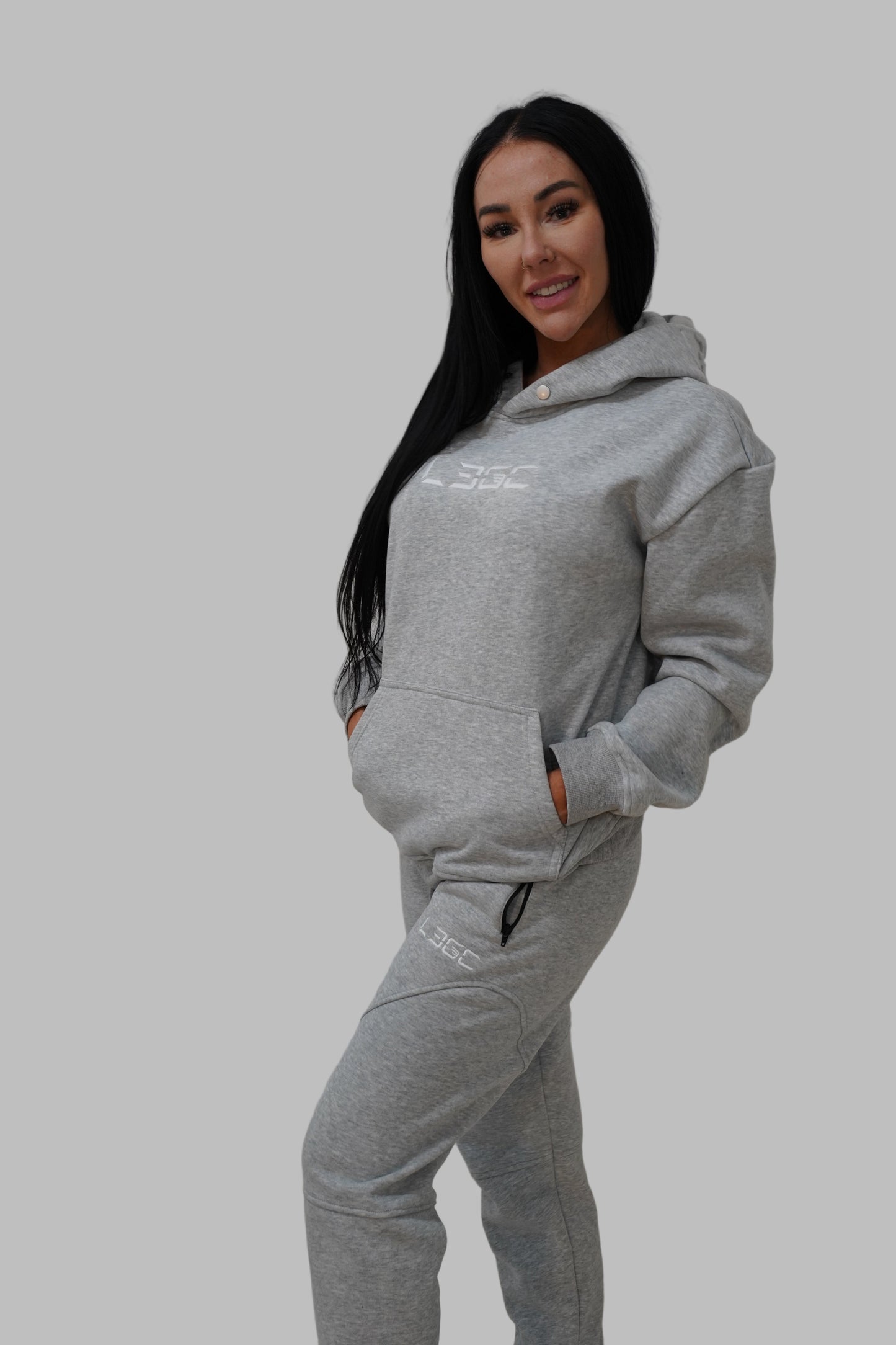 Person wearing a gray hoodie and pants on a white background