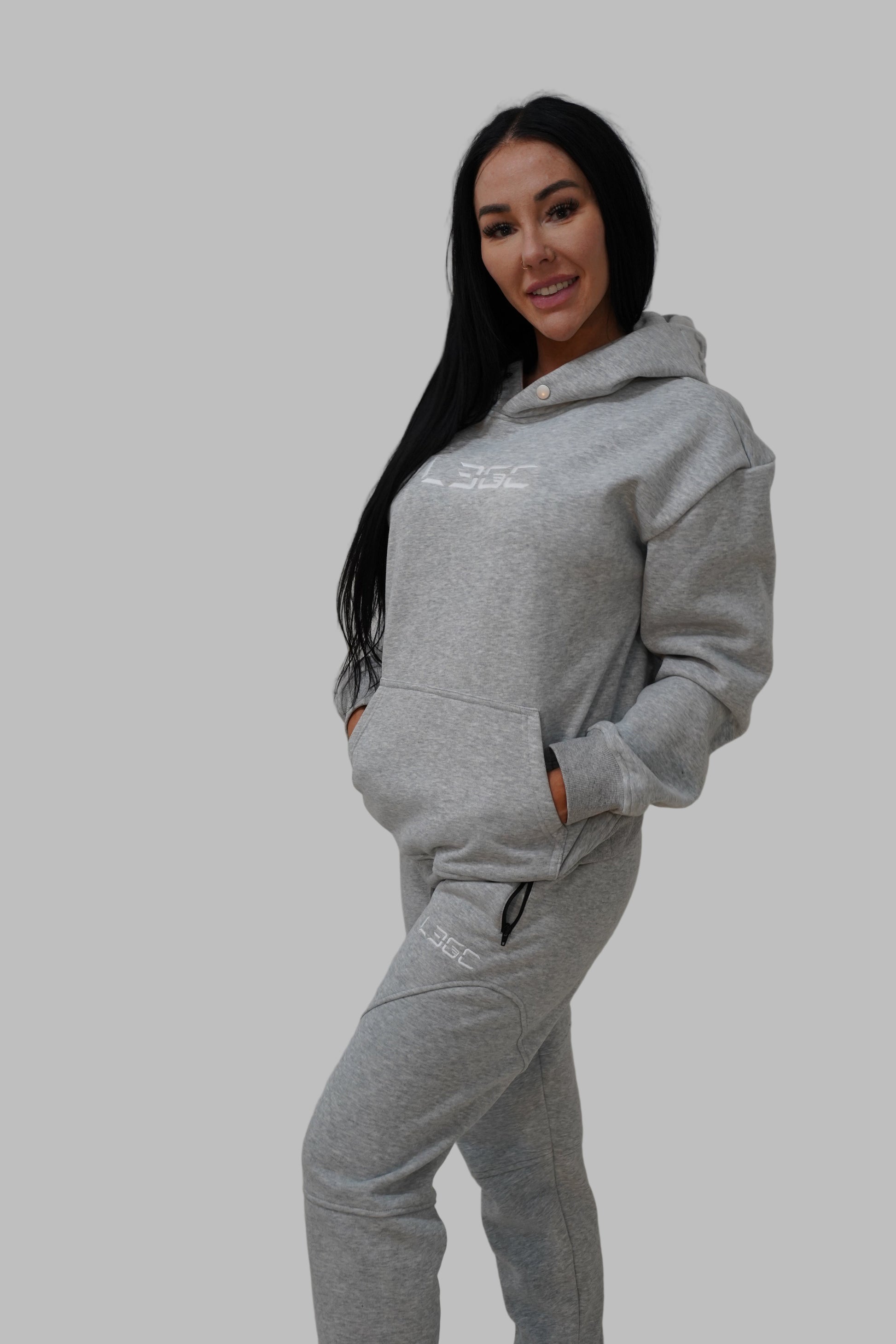 Person wearing a gray hoodie and pants on a white background