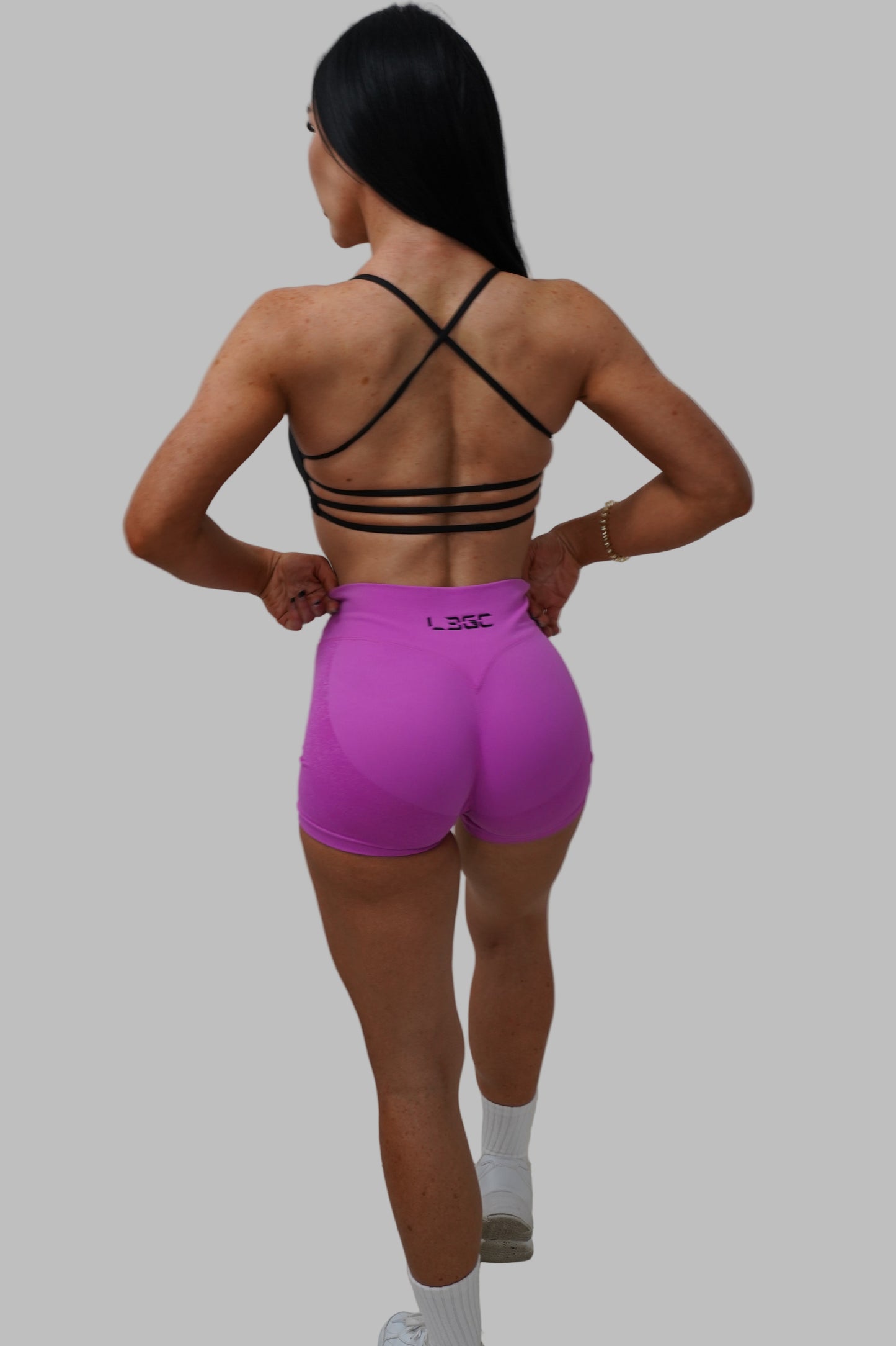 woman wearing a black strappy top and pink shorts.